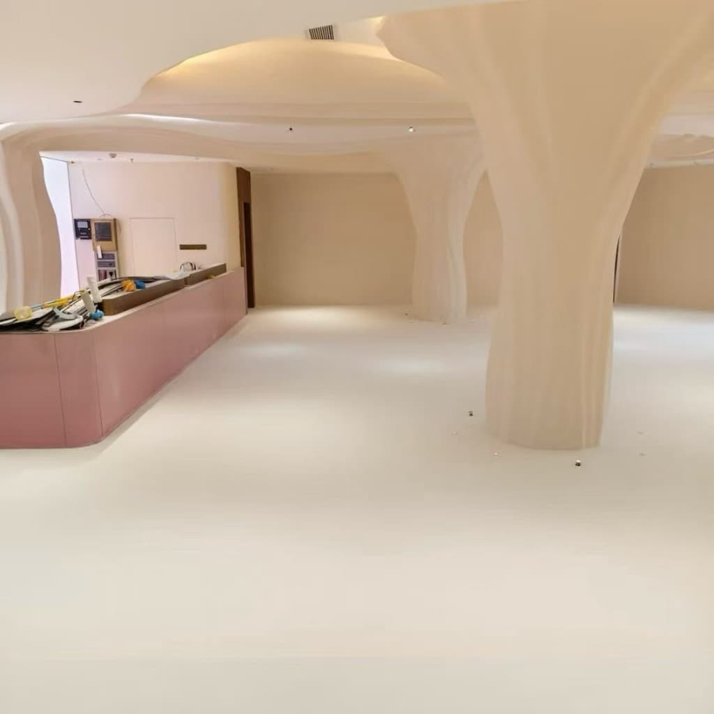 Boutique hotel lobby with three organic microcement mushroom columns flowing from the ceiling to a continuous warm-white microcement floor, with a soft-pink reception counter on the left