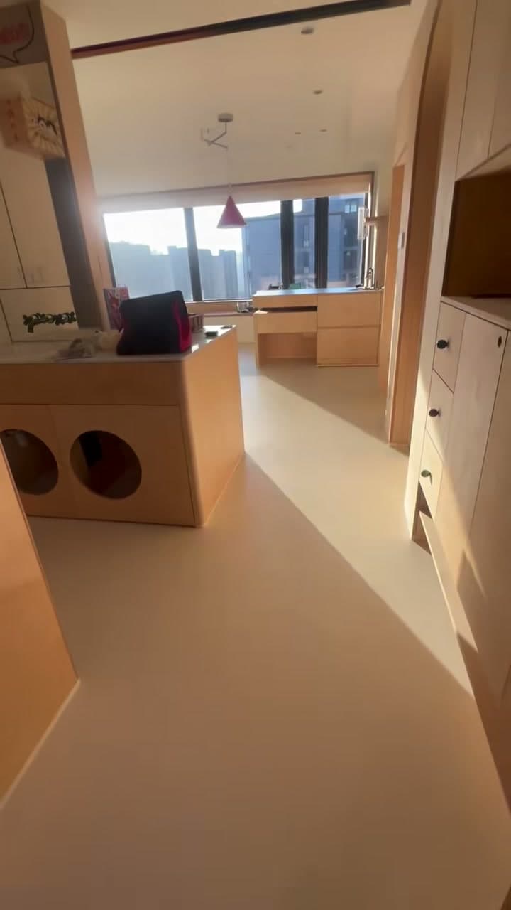Suite pantry / kitchenette in the same project — microcement floor running under timber millwork, sculpted column with two circular cut-outs